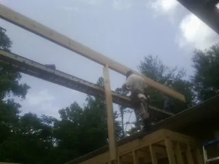 Carpenter setting a ridge beam over a new addition frame — Ice Dam Removal by Roofing Brothers in Early Branch