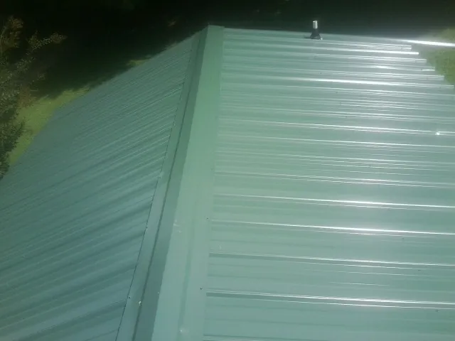 New green metal panels meeting at the ridge of a roof — Flat Roof Repair work by our crew in Early Branch