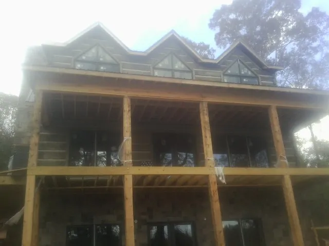 Dormers and porch framing on a large log home under construction — Roof Coating work by our crew in Early Branch
