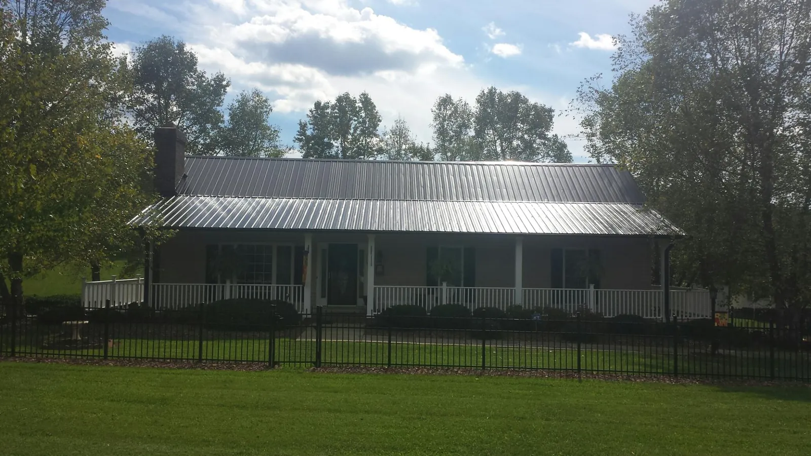 Gray metal roof on a brick ranch with a full width front porch — Gutter Guard Installation work by our crew in Early Branch