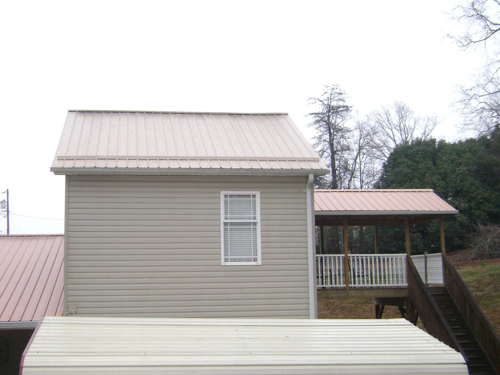 Tan metal roofs on a two story addition and attached porch, from a Roof Replacement job in Early Branch