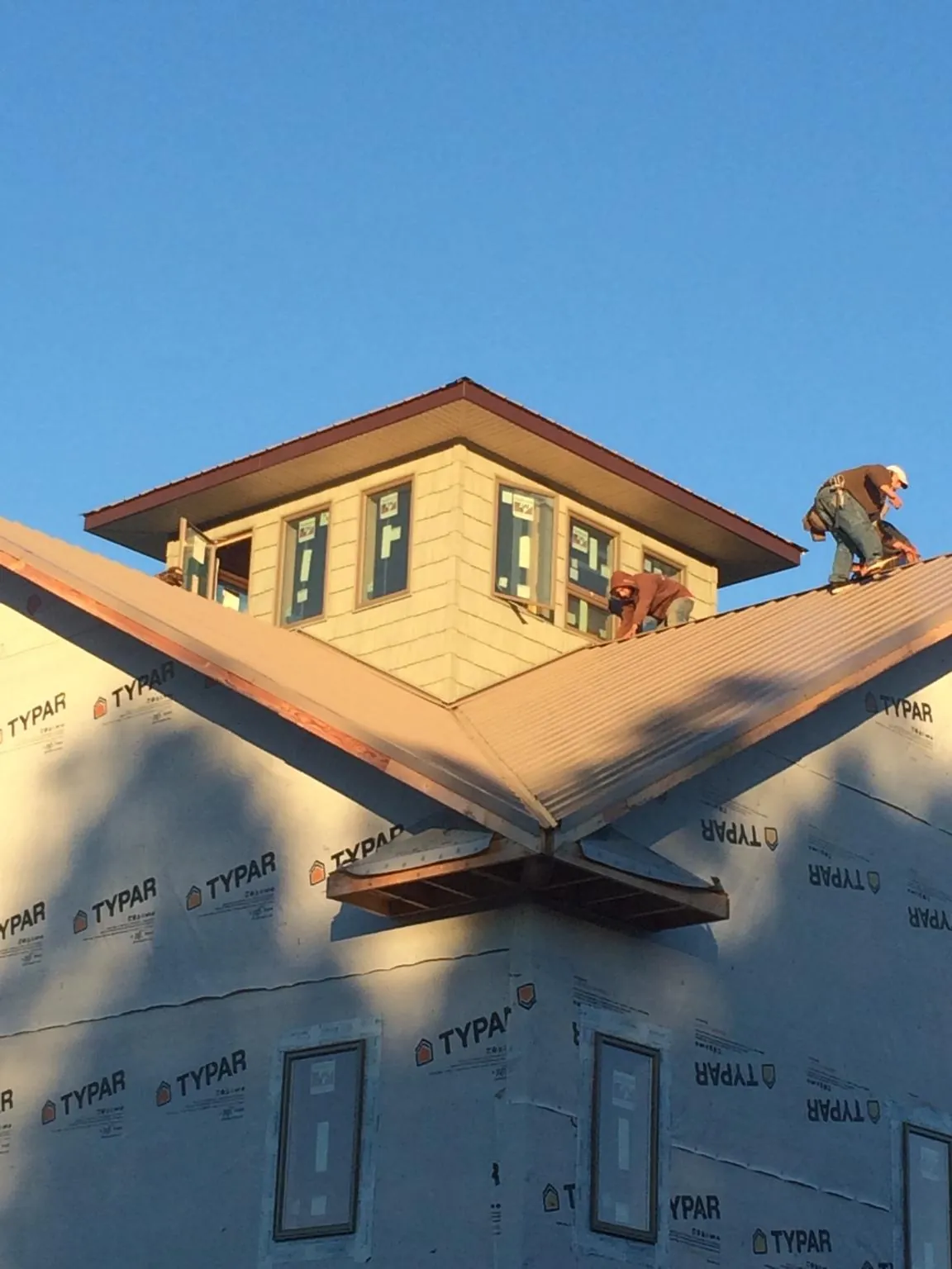 Roofers working around a rooftop cupola on a new metal roof at sunset — Roof Waterproofing in Early Branch by Roofing Brothers